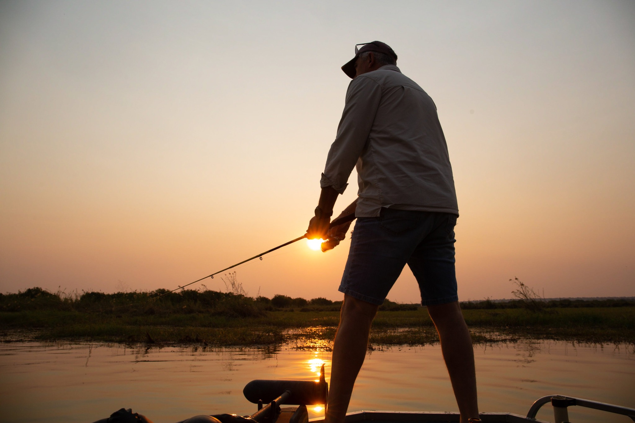 Guest fishing from a boat at sunset